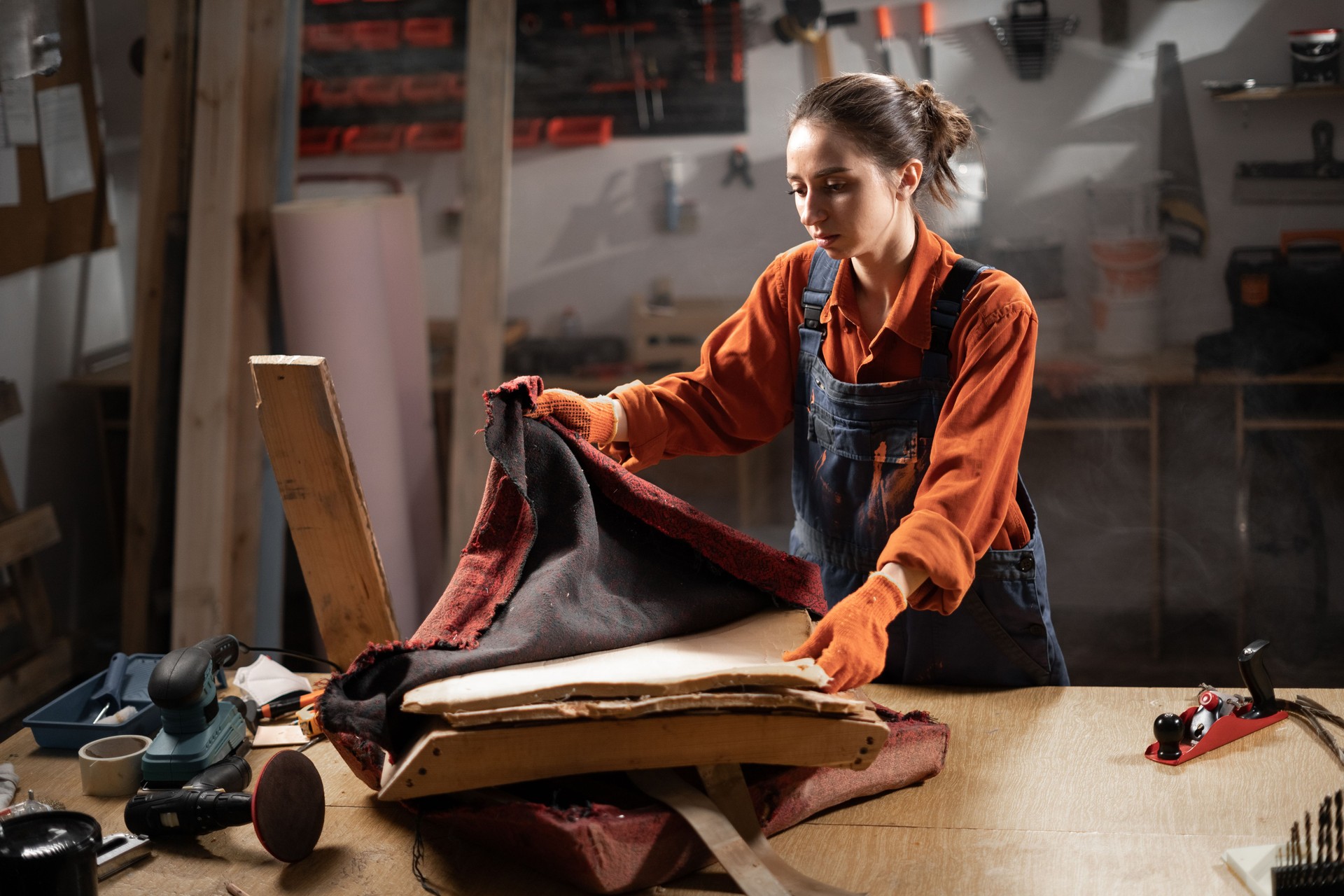 woman restoring old upholstered chair in workshop